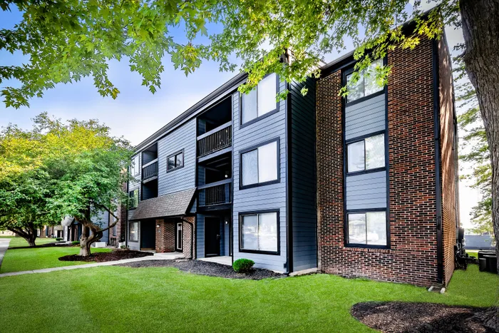 Pebble Point Apartments - Modern apartment building with sleek design, surrounded by lush greenery and bright blue sky, offering stylish urban living.