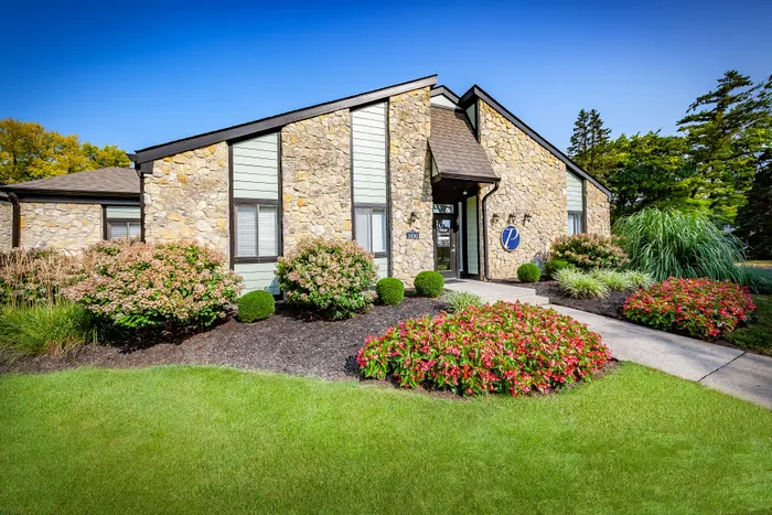 Pebble Point Apartments - Charming leasing office with lush landscaping, vibrant flowers, and a welcoming entrance.