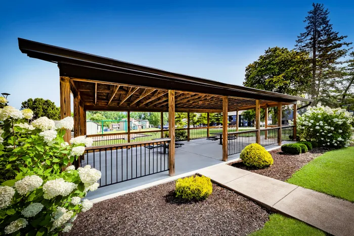 Pebble Point Apartments - Charming outdoor pavilion surrounded by lush greenery and blooming white flowers, perfect for relaxed gatherings.