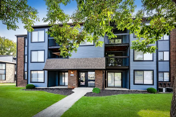 Pebble Point Apartments - Charming multi-family apartment complex highlighted by modern blue and brick facade, surrounded by lush green landscaping.