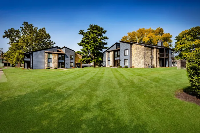 Pebble Point Apartments - Charming apartment complex with modern architecture and vibrant landscaped grounds, surrounded by lush greenery.