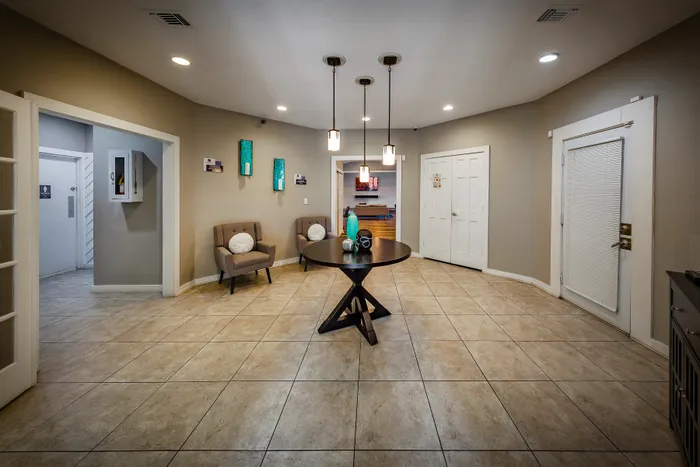 Pebble Point Apartments - Inviting leasing office entryway with modern pendant lighting, featuring cozy seating and elegant decor, perfect for a warm welcome.