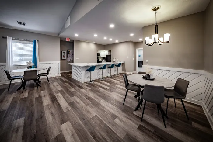 Pebble Point Apartments - Modern, open-concept dining and kitchen area with chic bar seating in the leasing office and stylish lighting, perfect for entertaining.