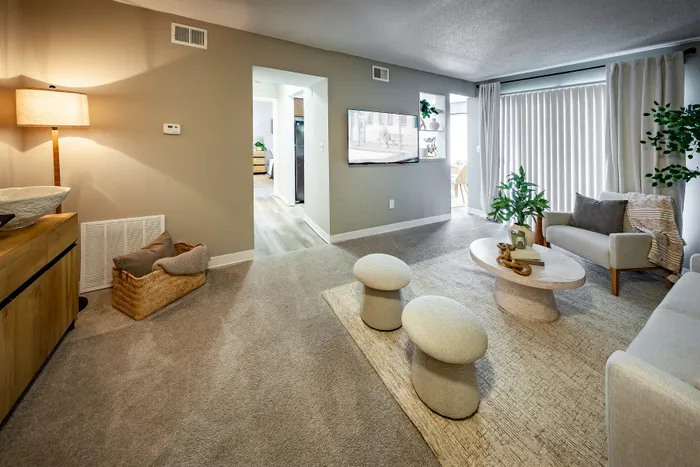 Pebble Point Apartments - Elegant living room with modern decor, featuring cozy seating, a stylish coffee table, and abundant natural light through large windows.