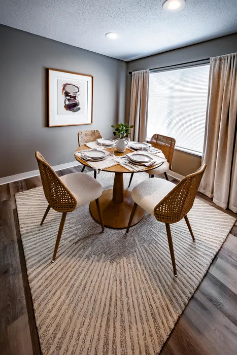 Pebble Point Apartments - Chic dining area with elegant round table, artistic decor, and cozy woven chairs under ambient lighting.