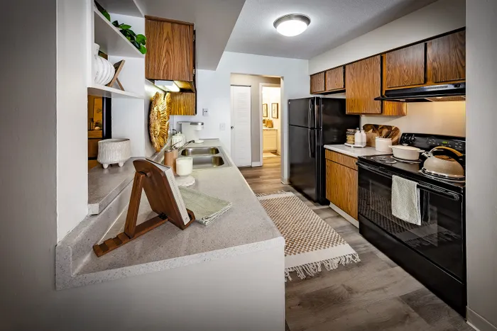 Pebble Point Apartments - Charming kitchen with wooden cabinets, modern appliances, and elegant countertop design for an inviting cooking experience.