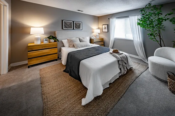 Pebble Point Apartments - Inviting bedroom with elegant decor, featuring a cozy bed, soft lighting, and stylish wooden furniture, enhanced by plush carpeting and natural accents.