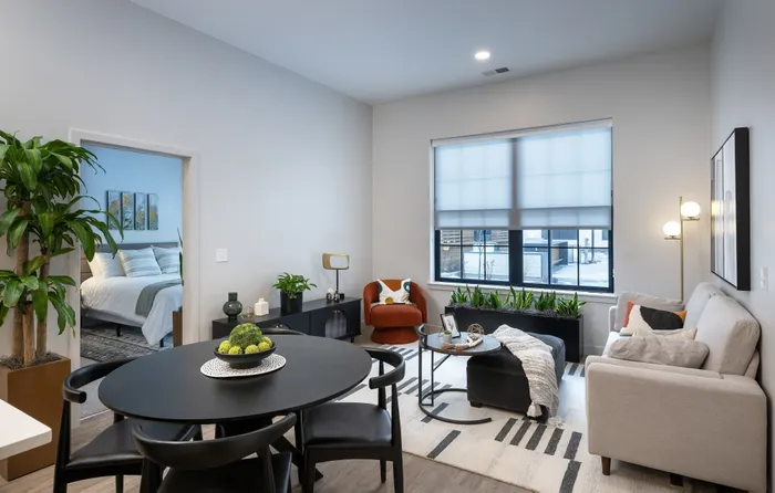The Elex Apartments - Sophisticated open-plan living room with modern decor, featuring a cozy seating area, elegant dining table, and abundant natural light.