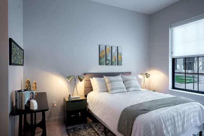 The Elex Apartments - Sunlit bedroom with modern decor, sleek bedside tables, and tasteful wall art, creating a cozy and inviting atmosphere.