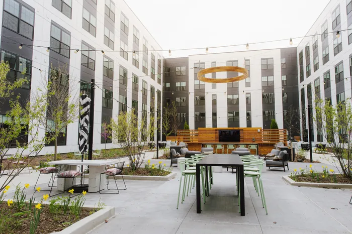 The Elex Apartments - Contemporary outdoor courtyard featuring stylish seating, modern string lights, and vibrant greenery, perfect for relaxation and social gatherings.