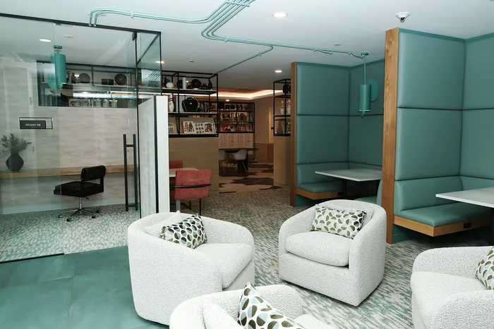 The Elex Apartments - Modern co-working lounge with plush white chairs, teal booth seating, and a stylish private glass meeting room.