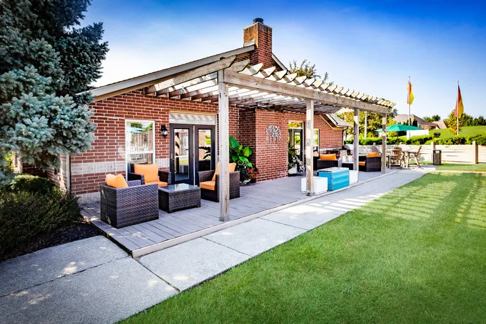 Charming outdoor patio with stylish pergola, cozy seating, and inviting brick facade, perfect for relaxing and entertaining.