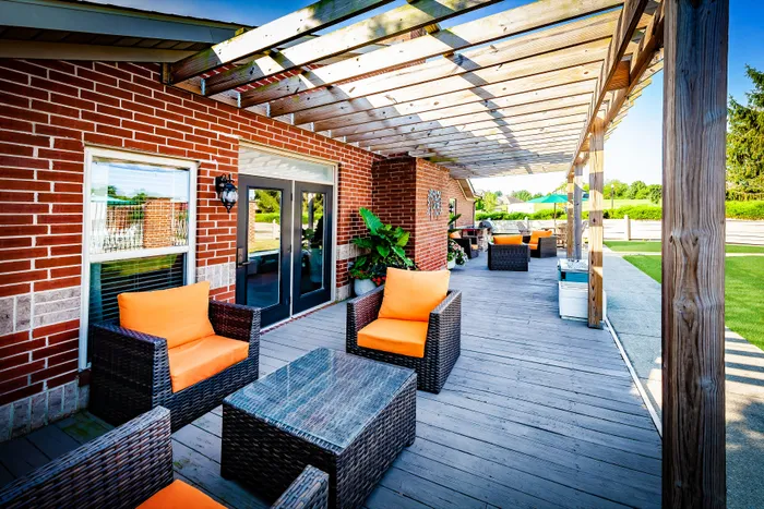 Charming outdoor patio with stylish wicker furniture, vibrant cushions, and inviting natural light under a wooden pergola.