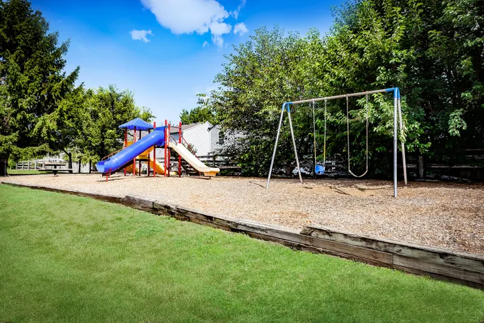 Charming apartment complex featuring a vibrant playground with swings and slides, ideal for families.