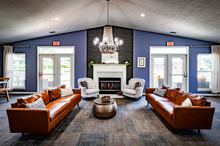 Elegant lounge area with plush brown sofas, a stylish chandelier, and a cozy fireplace, creating a warm and inviting atmosphere.