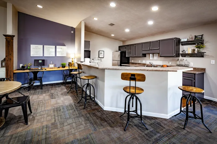 Modern kitchen with sleek black cabinets, a stylish breakfast bar with wooden stools, and a cozy workspace in the corner.