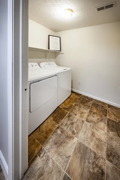 Bright and functional laundry room featuring modern washer and dryer set, elegant tile flooring, and minimalist decor.