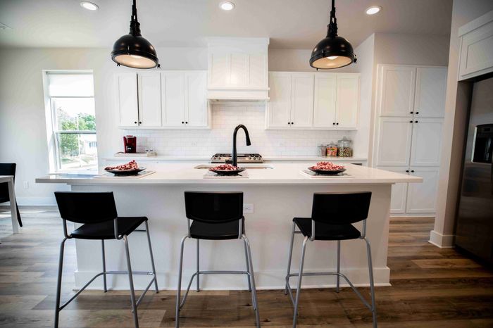 Modern kitchen with a sleek island, contemporary black fixtures, and elegant pendant lighting. Features white cabinetry, stainless steel appliances, and open layout ideal for entertaining.