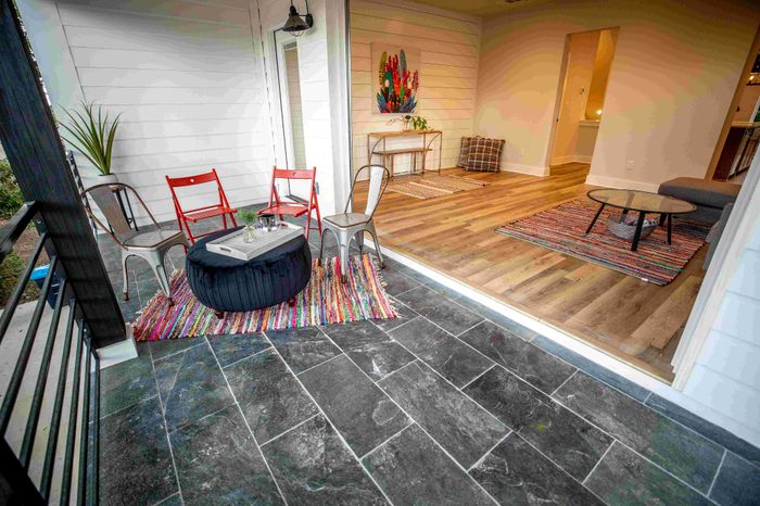 Charming covered patio with modern seating, connecting to a warm, inviting living space with vibrant decor and stylish flooring.
