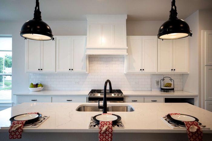 Stunning modern kitchen with elegant white cabinetry, sleek black fixtures, and ambient pendant lighting, perfect for culinary enthusiasts.