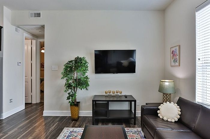 Contemporary living room with elegant decor, featuring a sleek wall-mounted TV, cozy leather sofa, and stylish floor lamp.