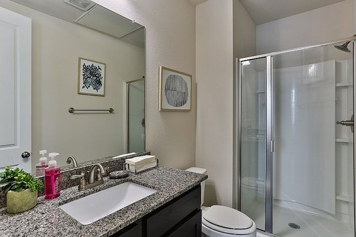 Modern bathroom with elegant granite countertop, sleek glass shower, and stylish decor.