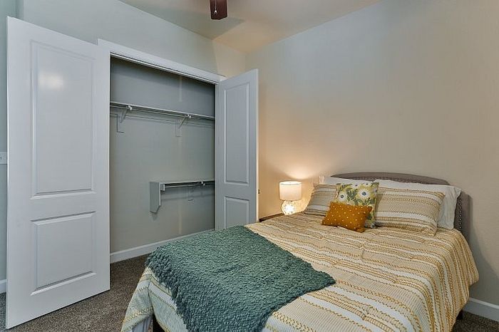 Cozy bedroom with a stylish bed, open closet space, and ambient lighting for relaxation.