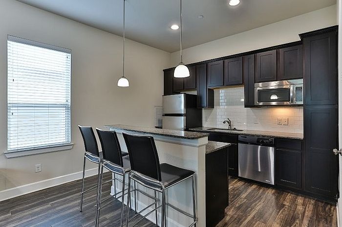 Modern kitchen with sleek cabinetry, stainless steel appliances, and a stylish breakfast bar with pendant lighting.