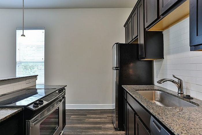 Modern kitchen with sleek granite countertops, dark wood cabinetry, and stainless steel appliances, perfect for culinary enthusiasts.