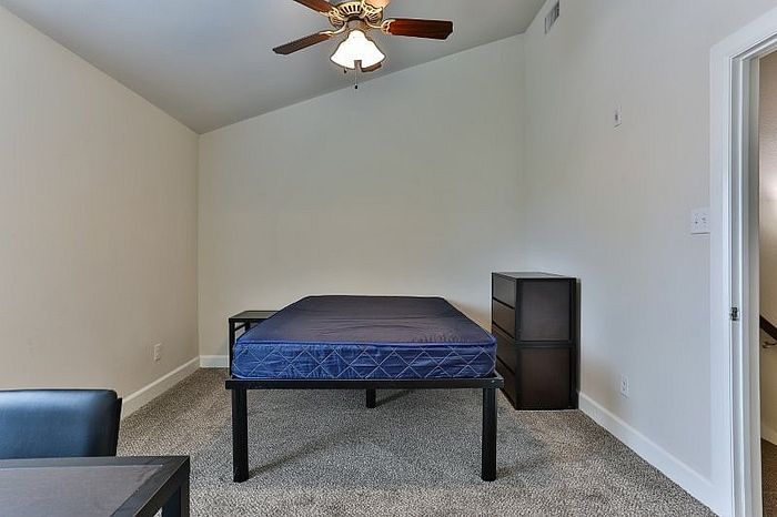 Inviting bedroom with plush carpet, ceiling fan, and ample natural light, designed for comfort and relaxation.