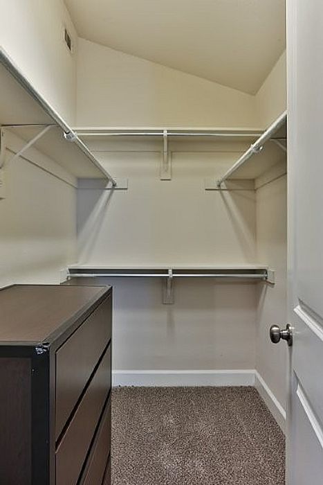 Spacious walk-in closet with ample shelving and a chic laminate dresser, perfect for organized living.