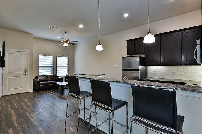 Modern open-concept apartment with sleek kitchen, stylish breakfast bar, and cozy living area.