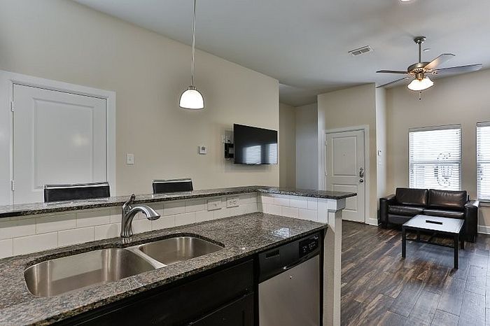 Modern open-concept living area with sleek kitchen, granite countertops, and bright windows overlooking cozy seating.