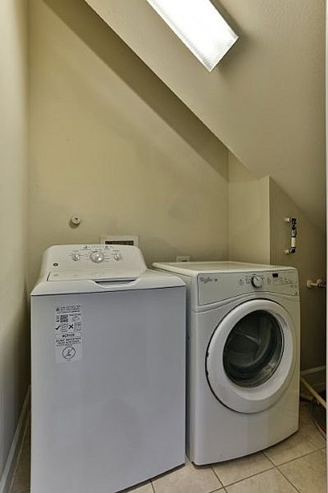 Modern laundry area with a sleek washer and dryer under a stylishly angled ceiling.