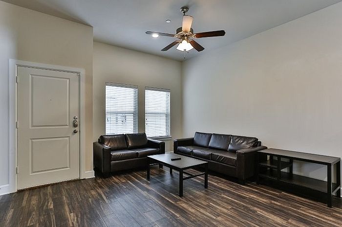 Modern living room with sleek dark wood floors, chic leather sofas, and ample natural light creating a welcoming ambiance.