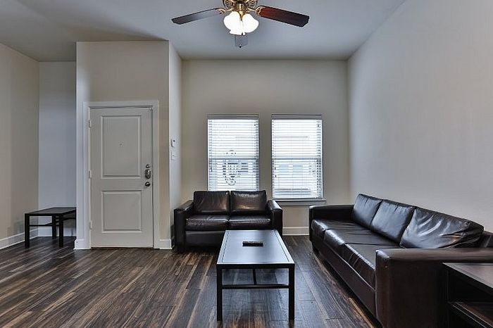 Modern living room showcasing sleek leather sofas, elegant wooden flooring, and abundant natural light.