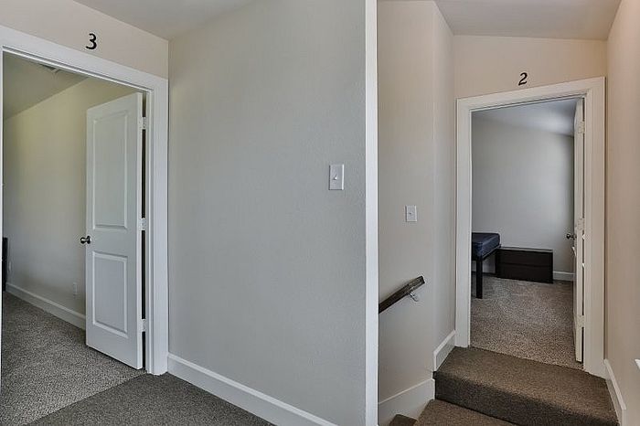 Inviting hallway showcasing elegant doorways leading to cozy carpeted bedrooms, creating a warm and welcoming atmosphere.