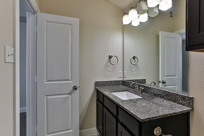 Modern bathroom featuring a sleek granite countertop, elegant lighting, and polished cabinetry.