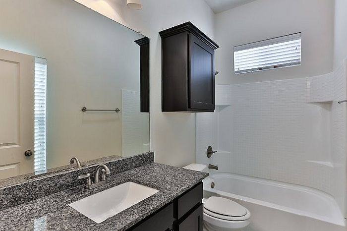 Elegant bathroom with granite countertop, sleek fixtures, and a cozy bathtub for relaxation.