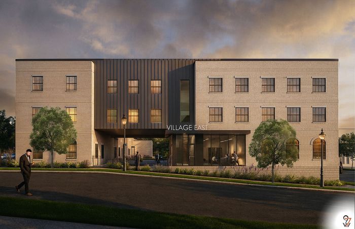 Elegant exterior of Village East apartment building with contemporary design, large windows, and lush greenery, illuminated at dusk.