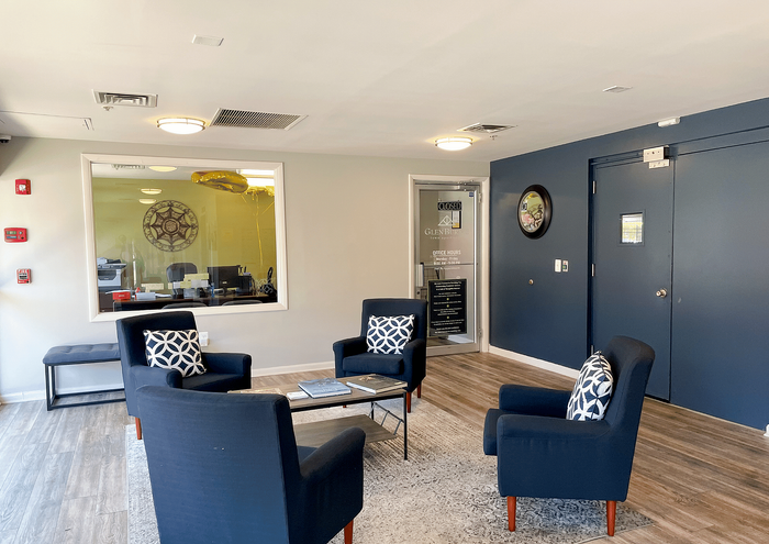 Bright and modern office lounge with navy blue armchairs and stylish decor.