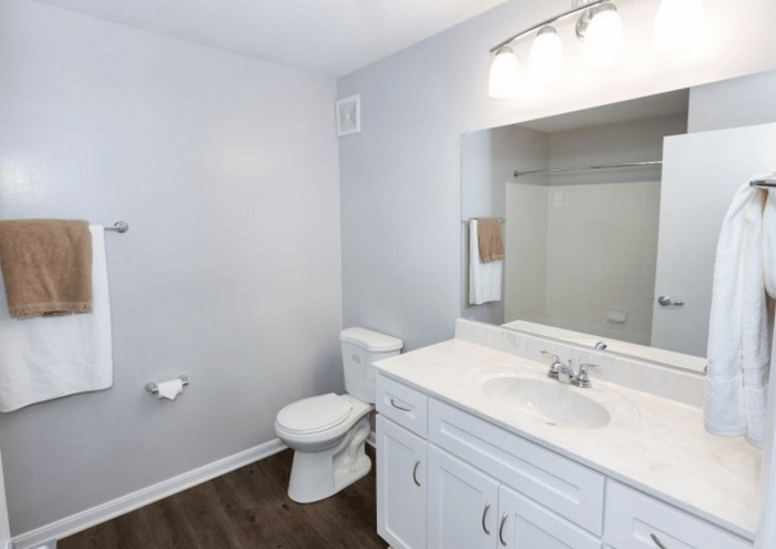 Modern bathroom with sleek fixtures, white cabinetry, and a large mirror above the sink area.