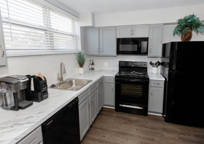 Sleek kitchen interior featuring modern appliances, grey cabinetry, and marble countertops.