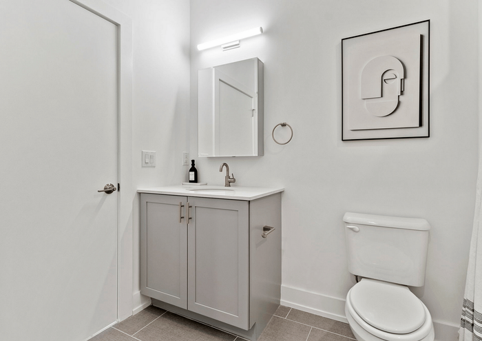 Sleek modern bathroom with minimalist decor, featuring a stylish vanity, mirror, and abstract wall art.