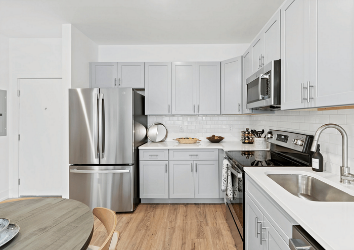 Modern kitchen featuring sleek grey cabinetry, stainless steel appliances, and a hardwood floor.
