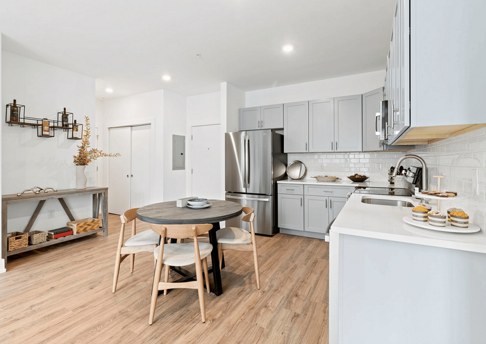 Bright modern kitchen with gray cabinets, stainless steel appliances, and a cozy wooden dining area.