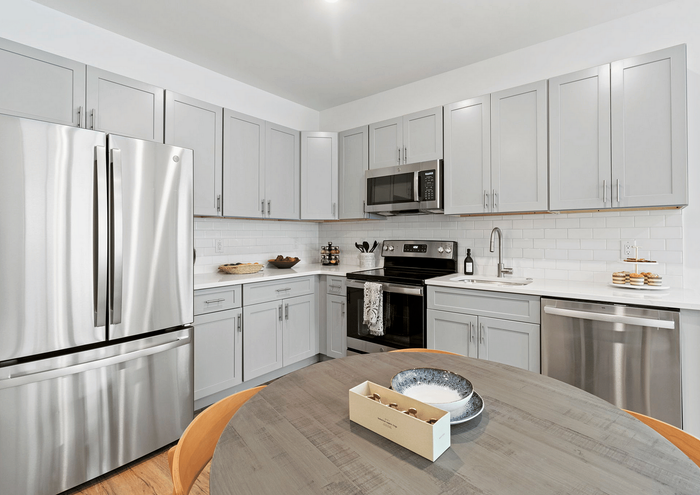 Bright contemporary kitchen with stainless steel appliances, gray cabinetry, and white subway tile backsplash.