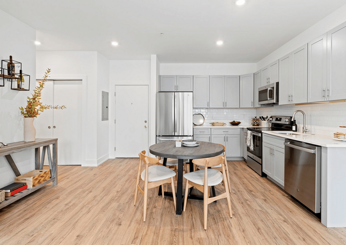 Modern kitchen with sleek gray cabinets, stainless steel appliances, and wooden dining set.