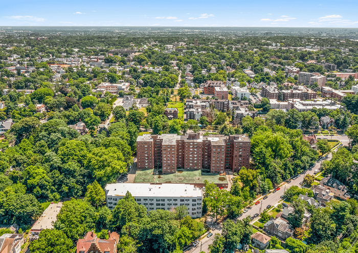 Aerial view of a residential complex surrounded by lush greenery in a vibrant cityscape.