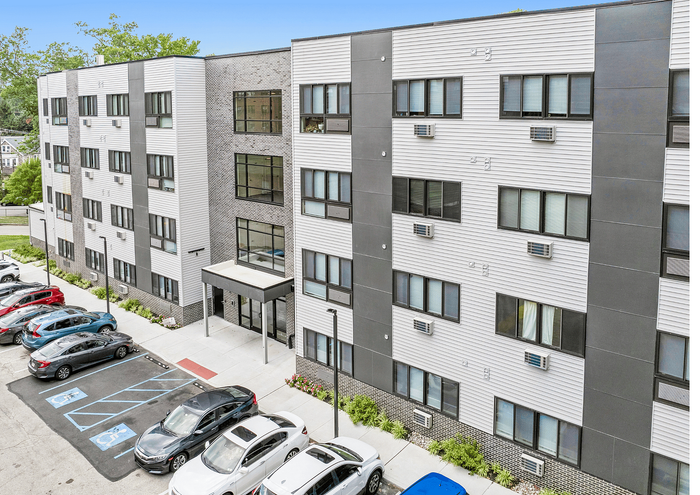 Modern apartment building with sleek design and ample parking area.